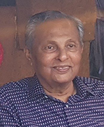 Portrait of Nihal Abeysekara smiling in a patterned blue shirt
