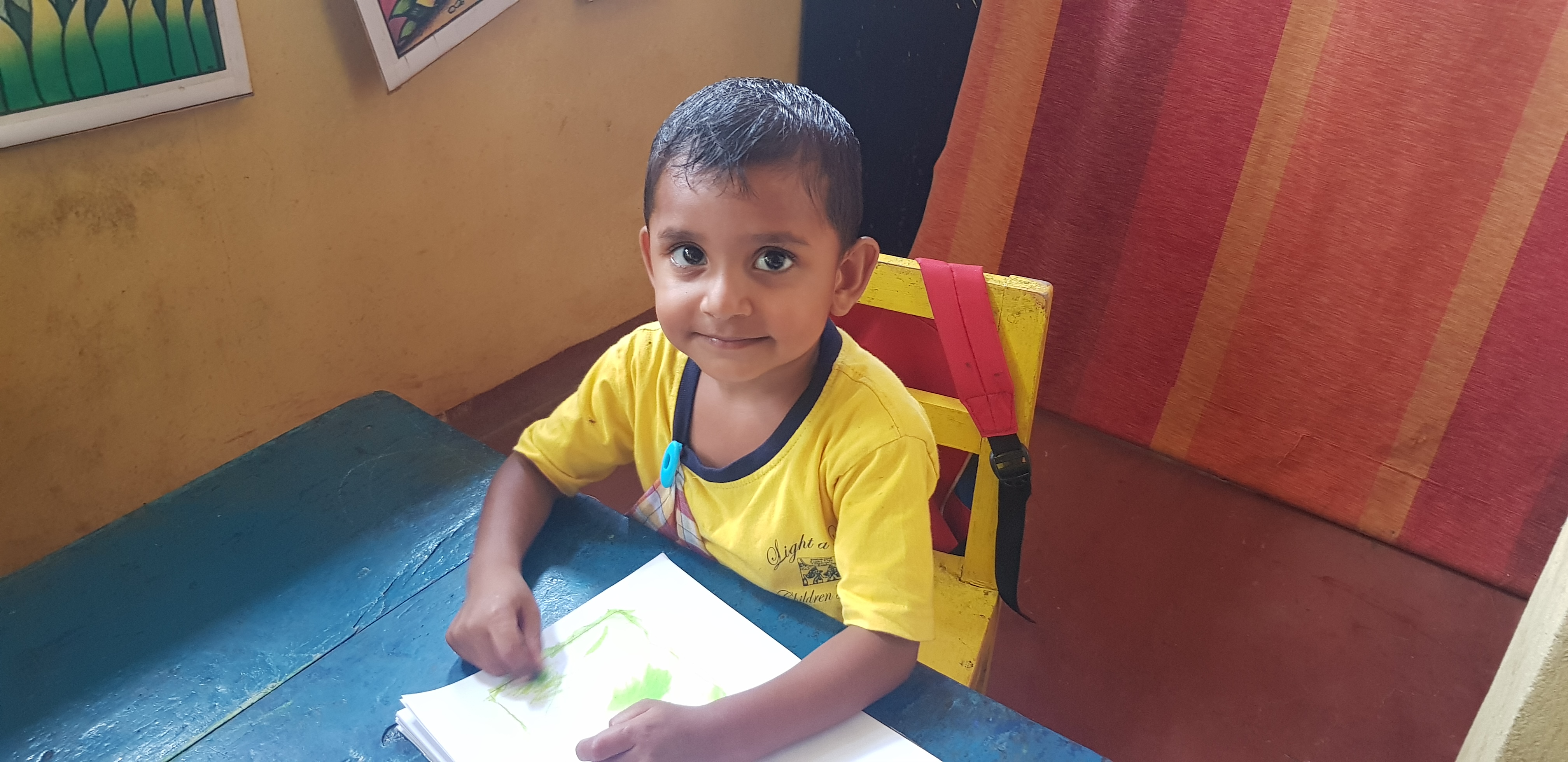 A child in a Light a Life uniform drawing at preschool