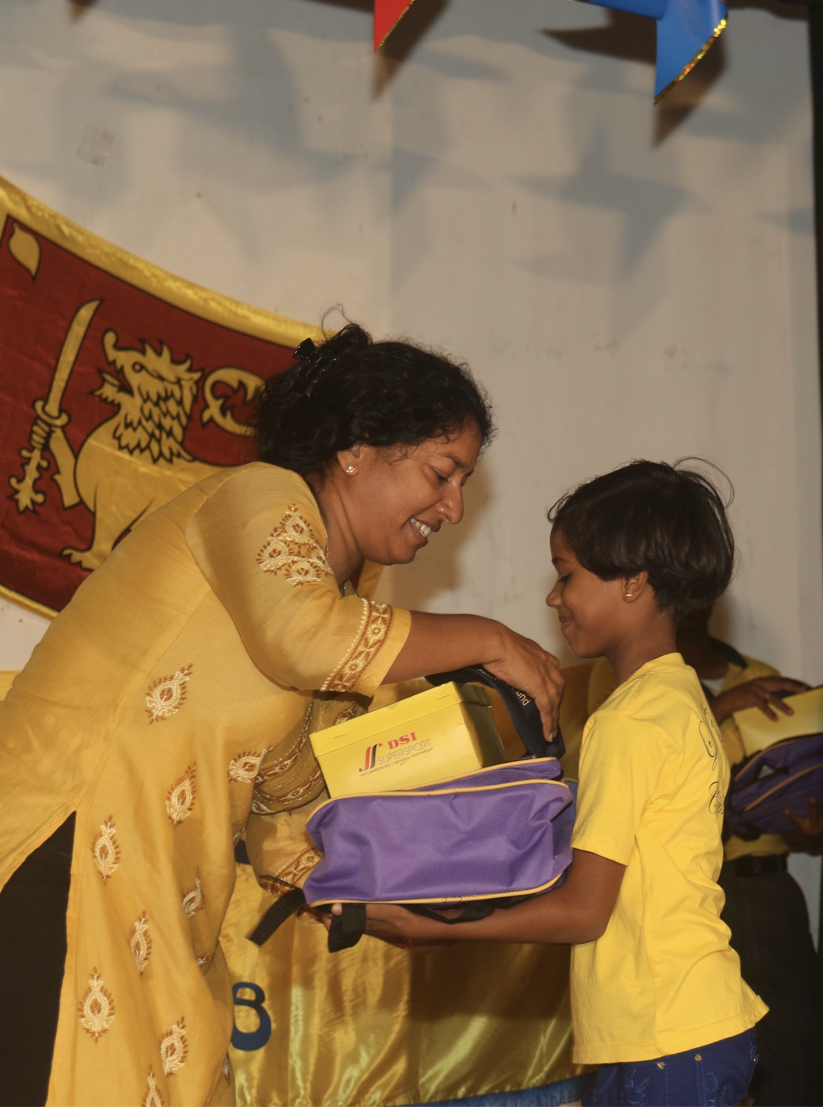 A Light a Life trustee handing a school kit to a smiling scholarship student